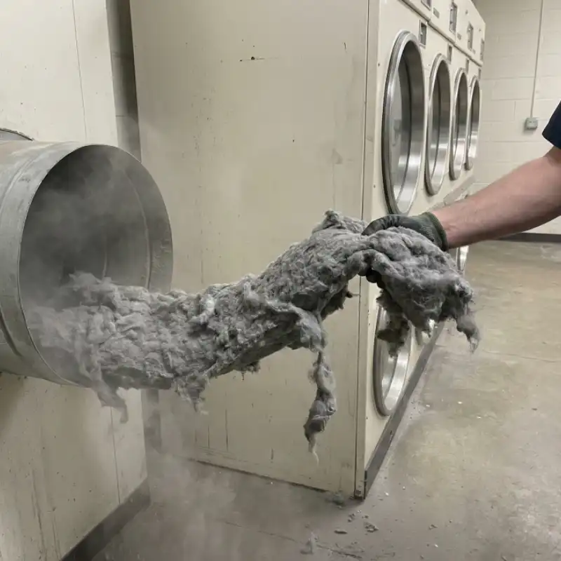 Massive accumulation of lint being removed from a commercial dryer exhaust system.